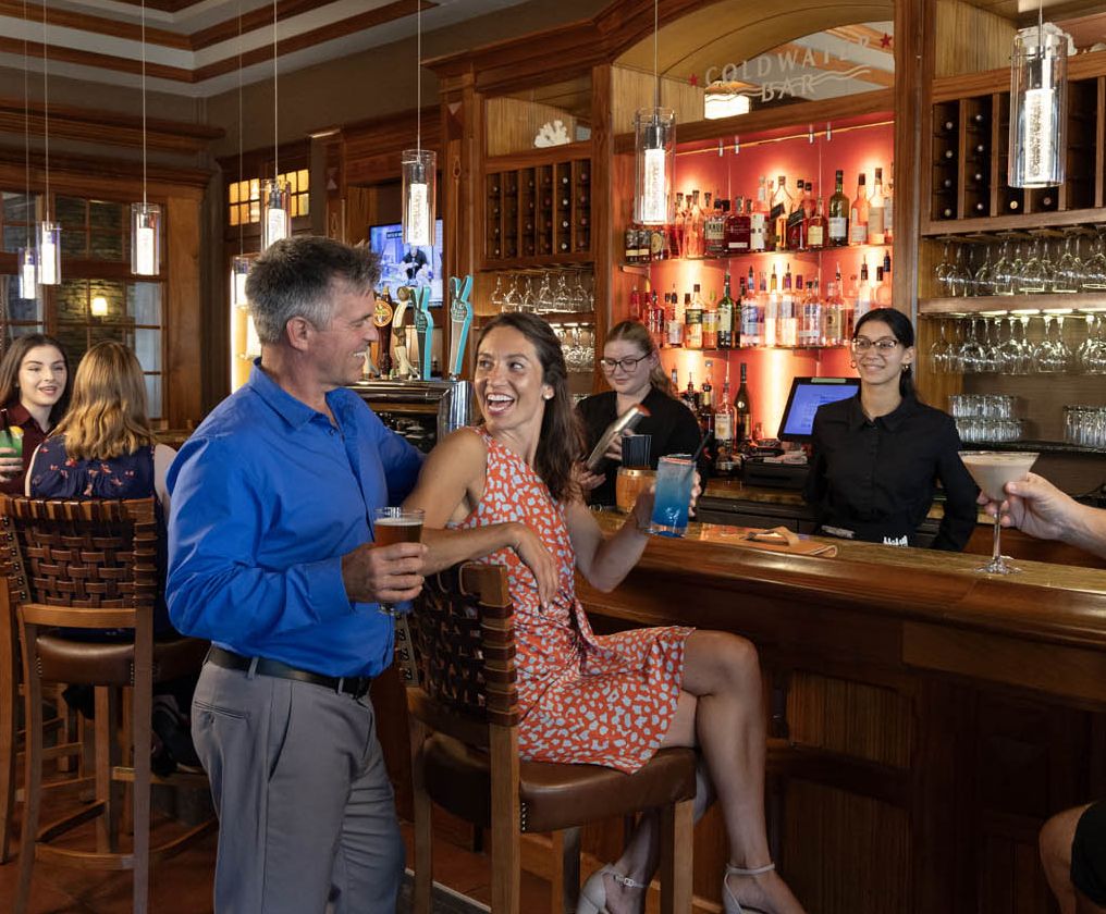 A group of people are bring served drinks from the friendly bartender at the Coldwater Bar