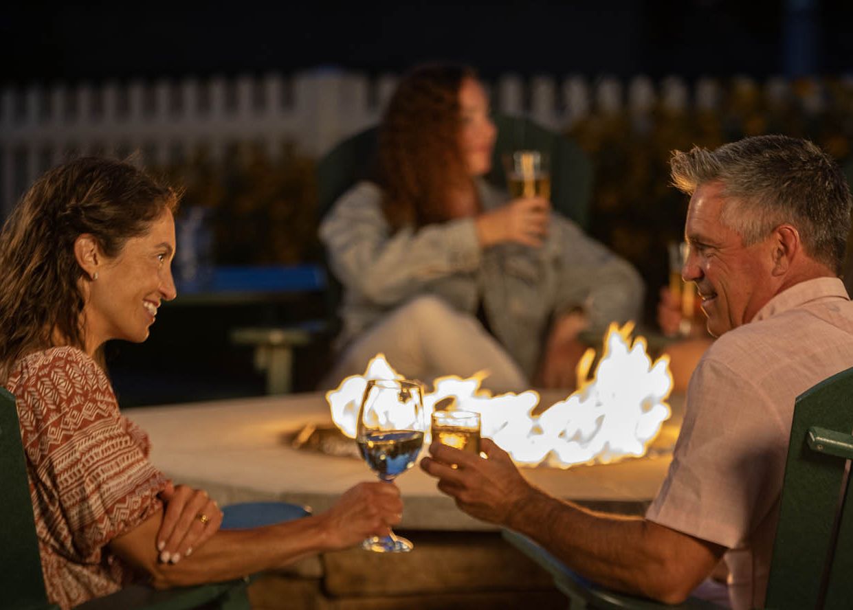 A couple relaxing with drinks by the outdoor fire pits
